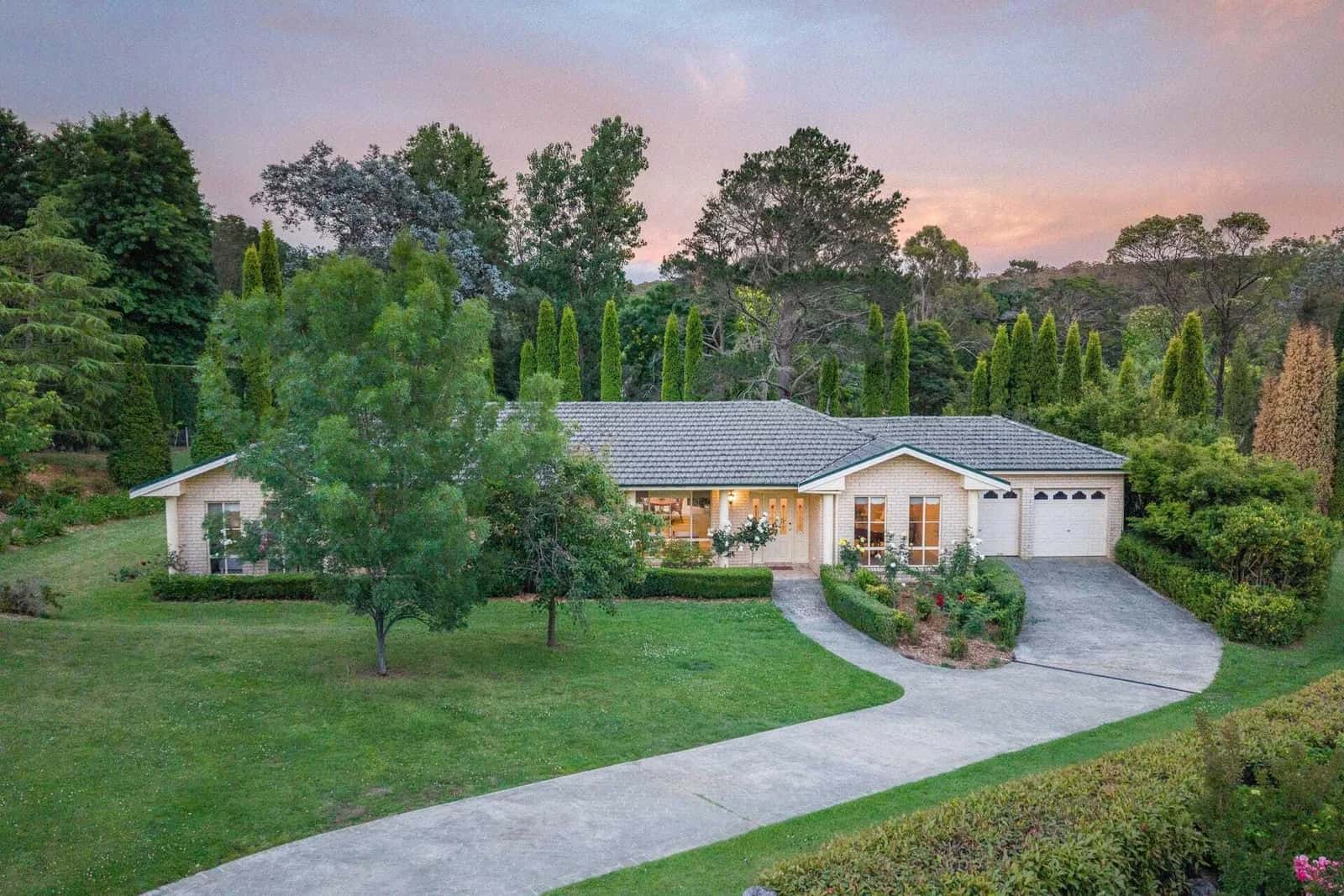 10 Copplestone Lane, Bowral viewed at dusk across the front lawn and curved driveway