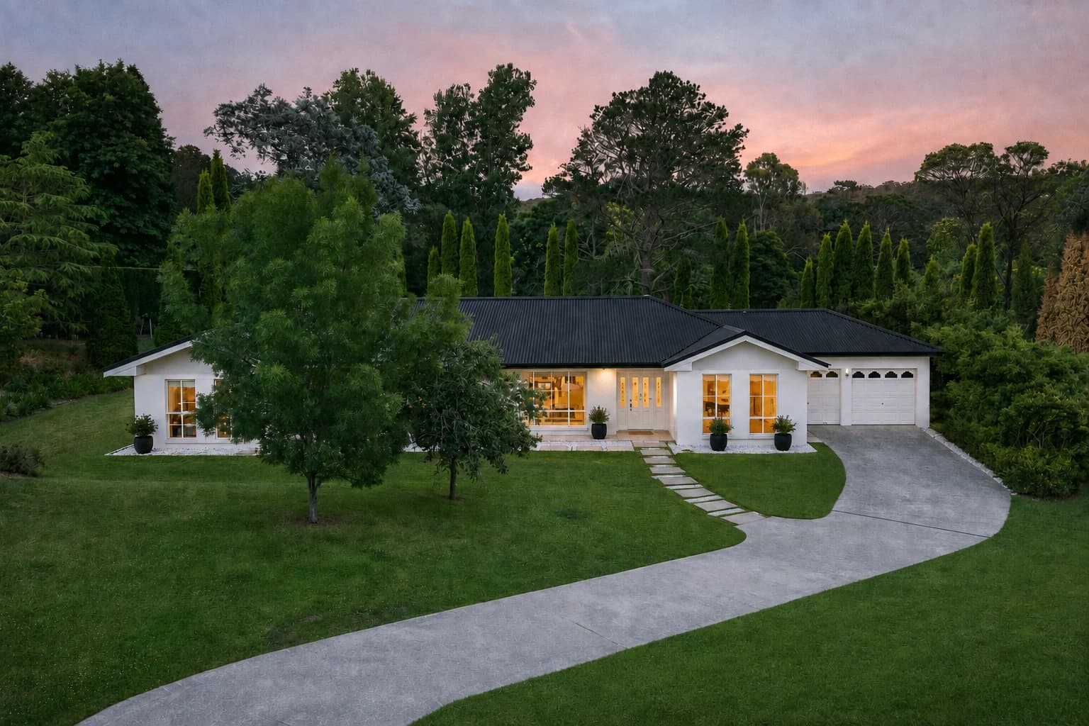 Artist's impression of the home at dusk with white render, a black metal roof, warm window lighting, black planters and a stone entry path beside the curved driveway